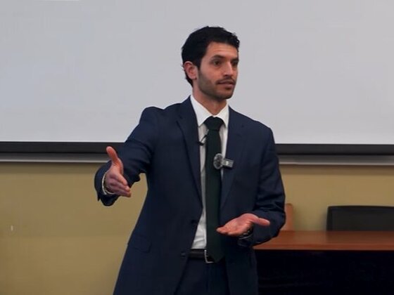 Christian Carmody speaking in a navy suit at a workshop